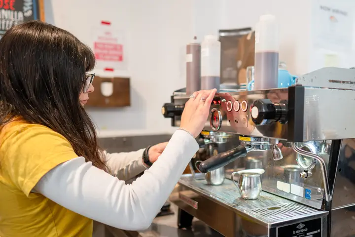 A barista pulling shots at the espresso machine behind the bar at Blue House Cafe.